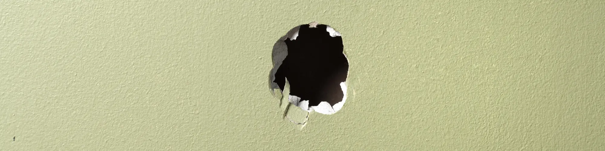 un trou dans un mur en placo peint en vert